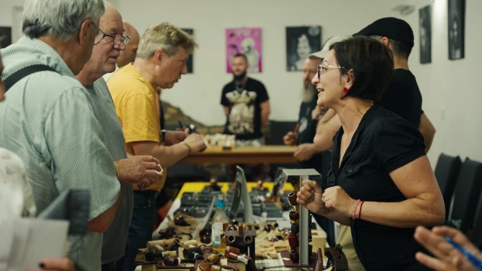 Érdeklődő látogatók válogatják és vizsgálják a kézműves pipákat